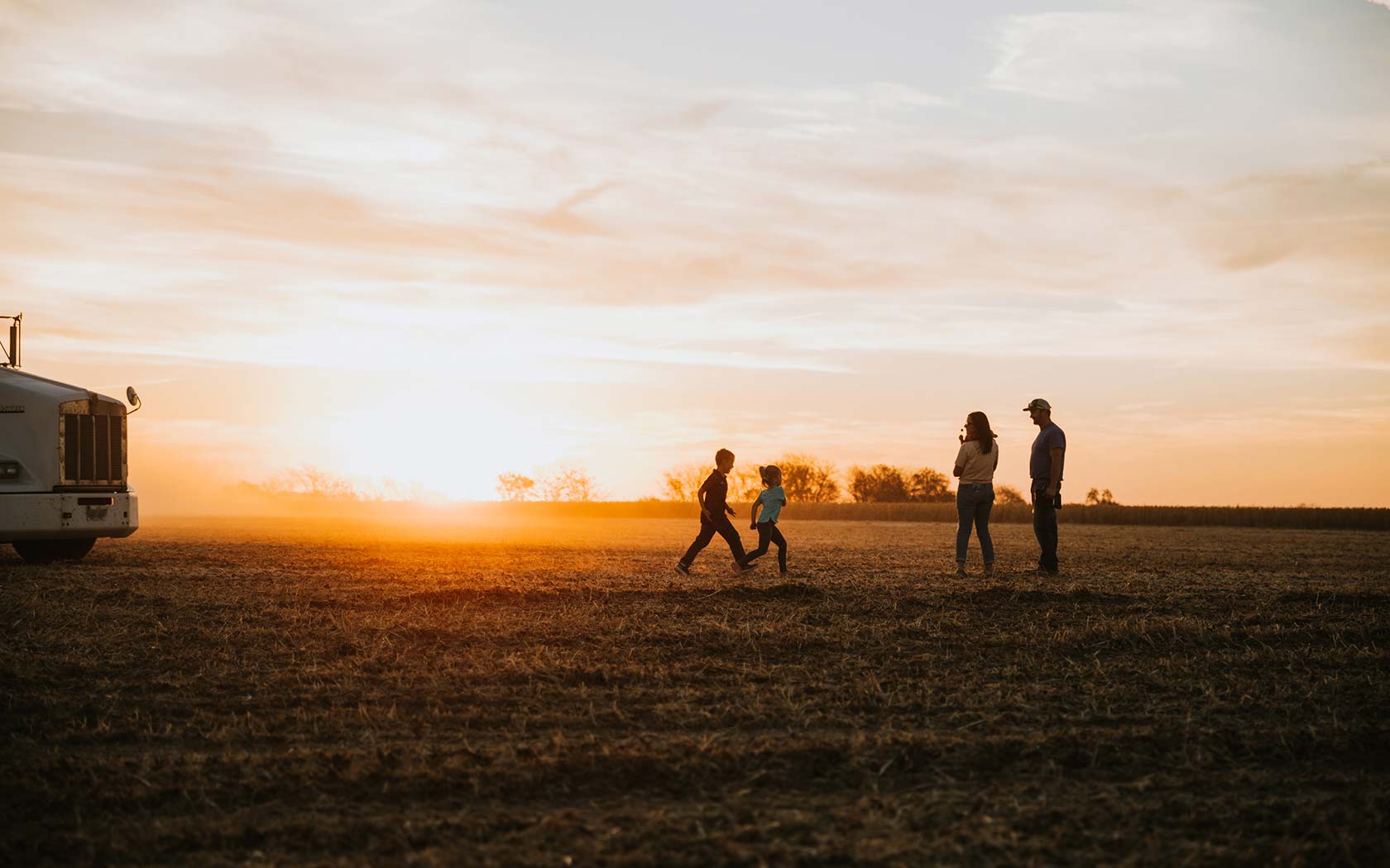 Family in a farm field at sunset