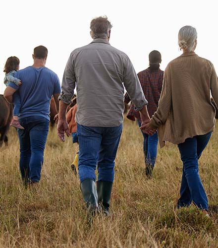 A group of people walking away in a field.