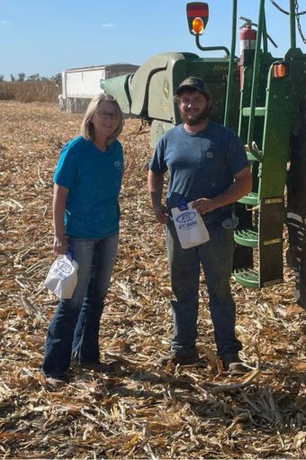 A BTC Bank employee standing next to a farmer in a field by a combine