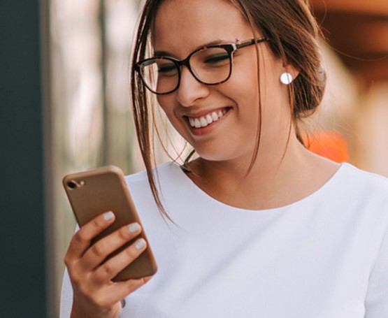Woman smiling as she reads a message on her phone