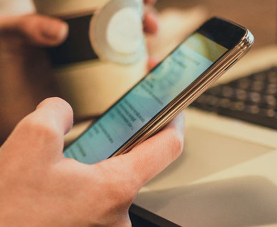 Person holding their phone while at their computer